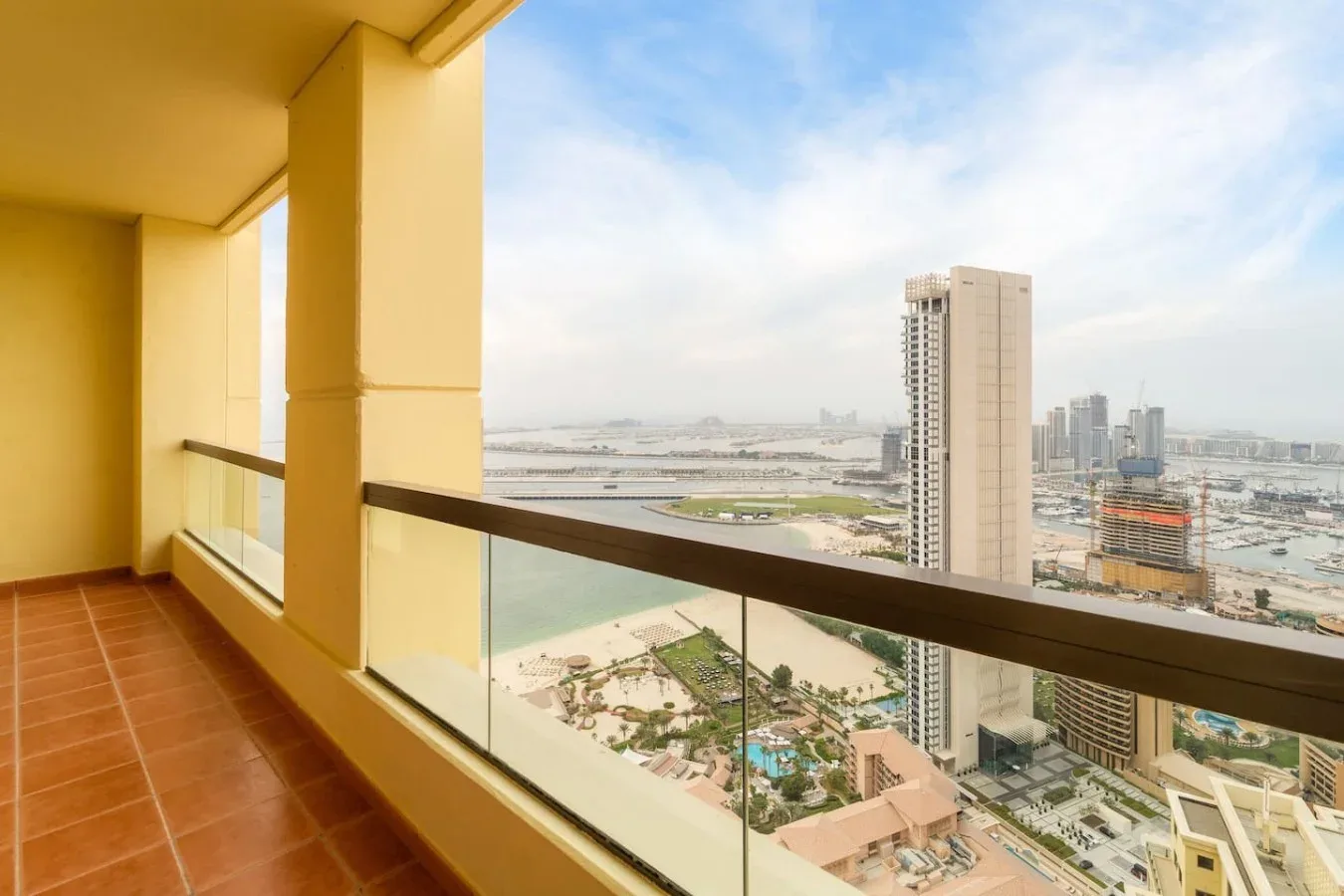 A balcony overlooks a waterfront cityscape through a glass railing.
