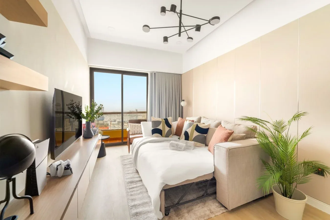 A bright living room with a sectional sofa, television, and large window.