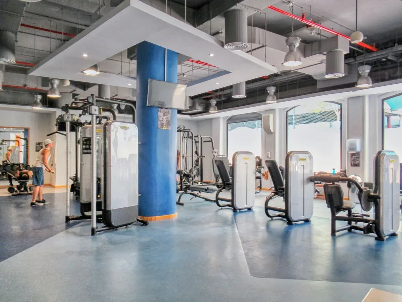 A gym with exercise machines and a blue support column.
