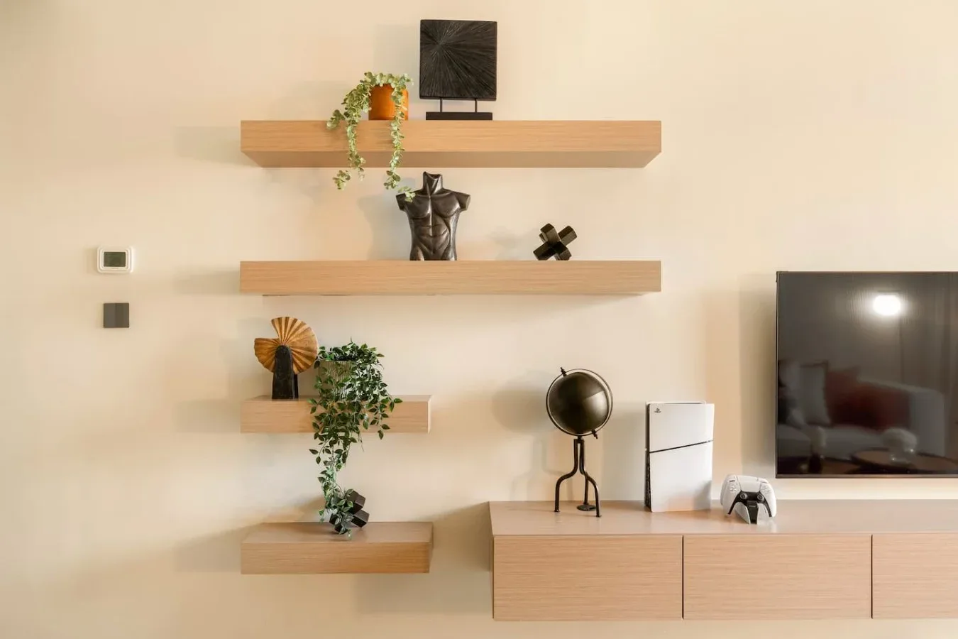 A living room wall with floating shelves, decorative objects, and a television.
