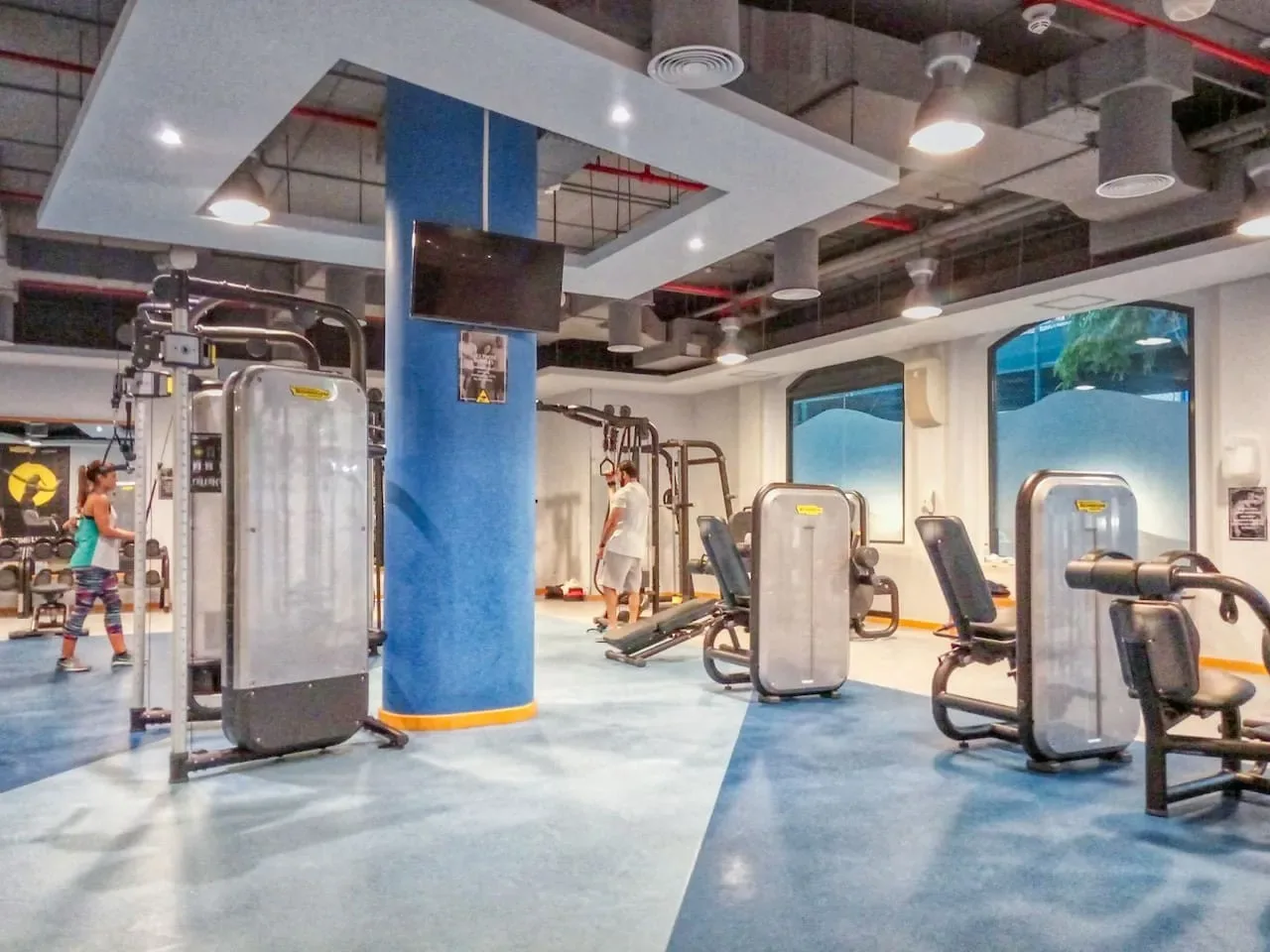 A gym with exercise machines and people working out.