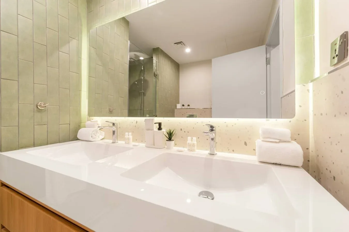 A bathroom vanity with two sinks sits beneath a wide mirror.