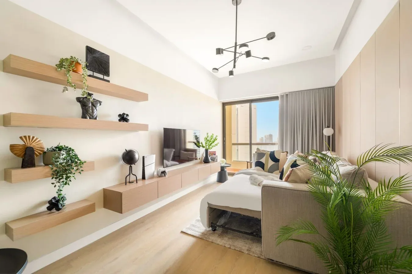 A bright living room with a television, seating, and large windows.