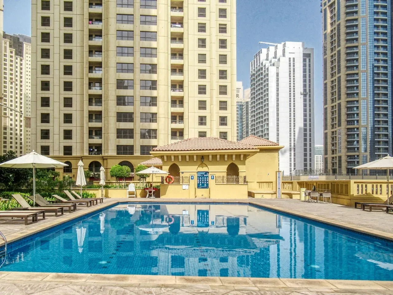 An outdoor swimming pool sits among tall urban apartment buildings.