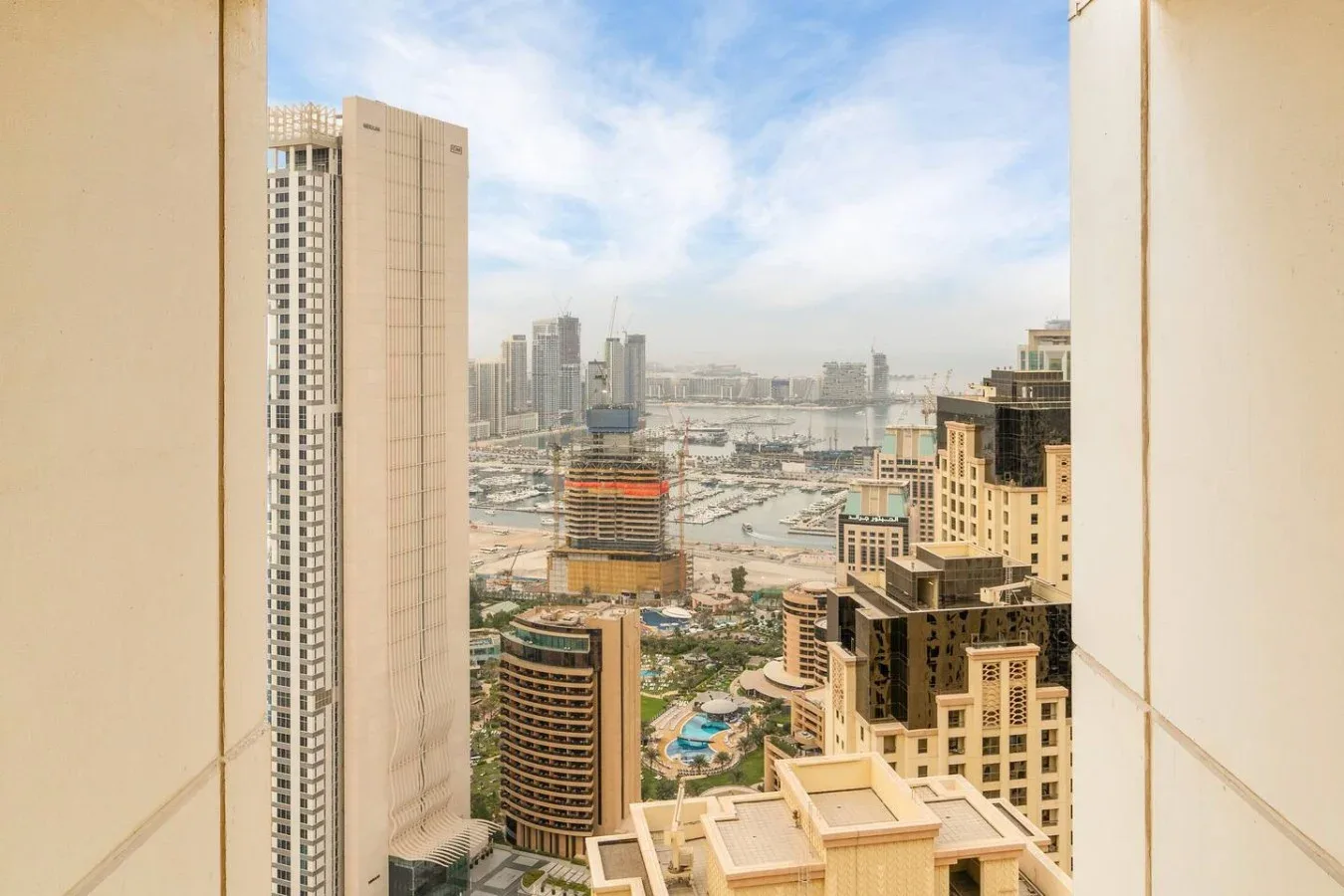 Cityscape viewed through a window, with high-rise buildings and a marina.