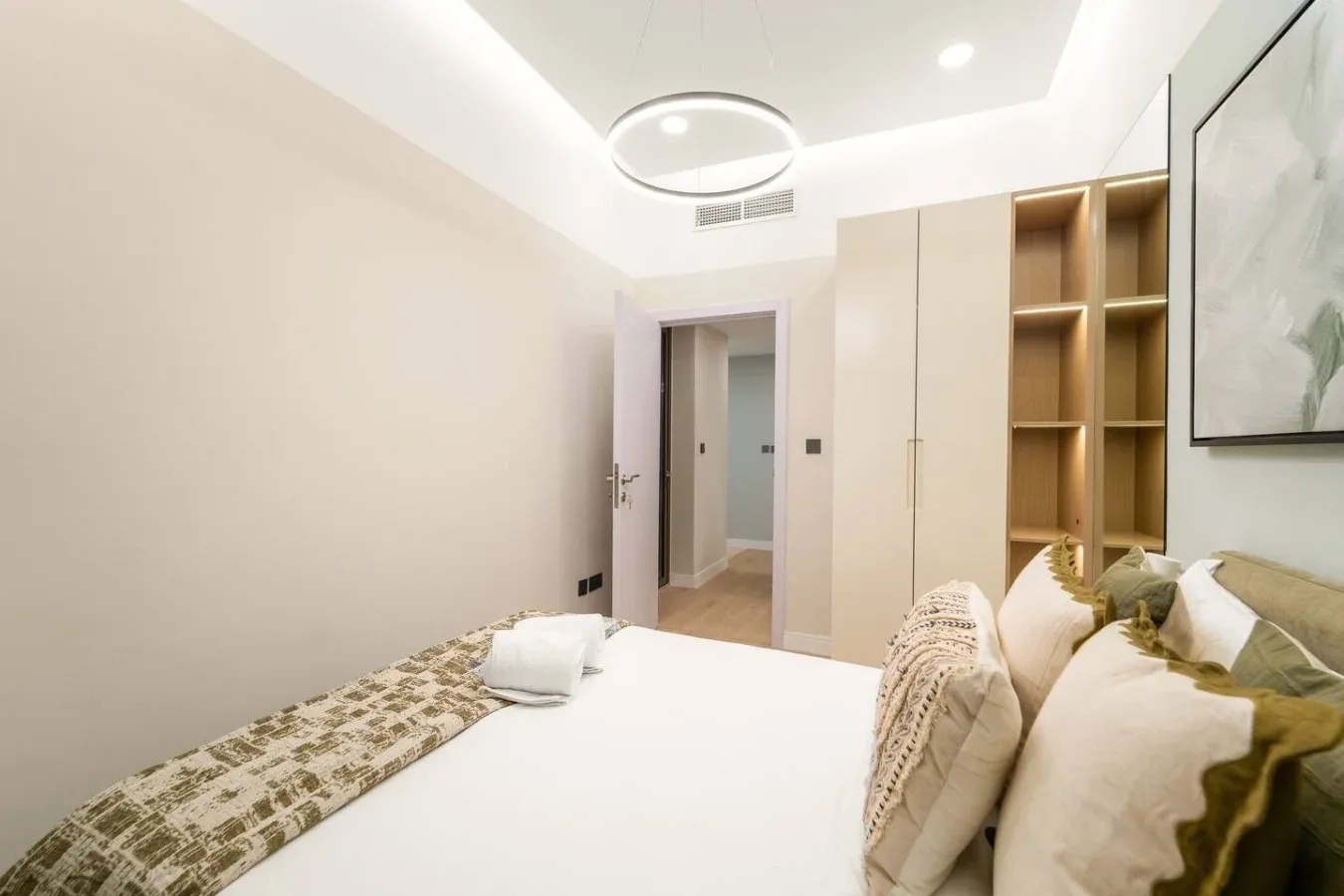 A bedroom with a bed, pillows, and open shelving beside the doorway.