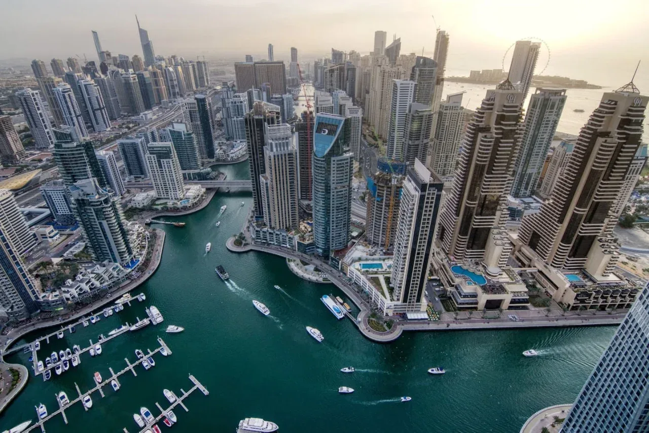 Aerial view of a waterfront skyline with high-rise buildings and boats in the marina.