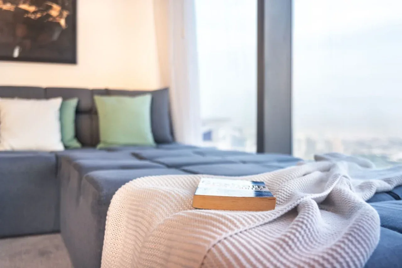A bedroom with a bed, green pillows, and a folded blanket.