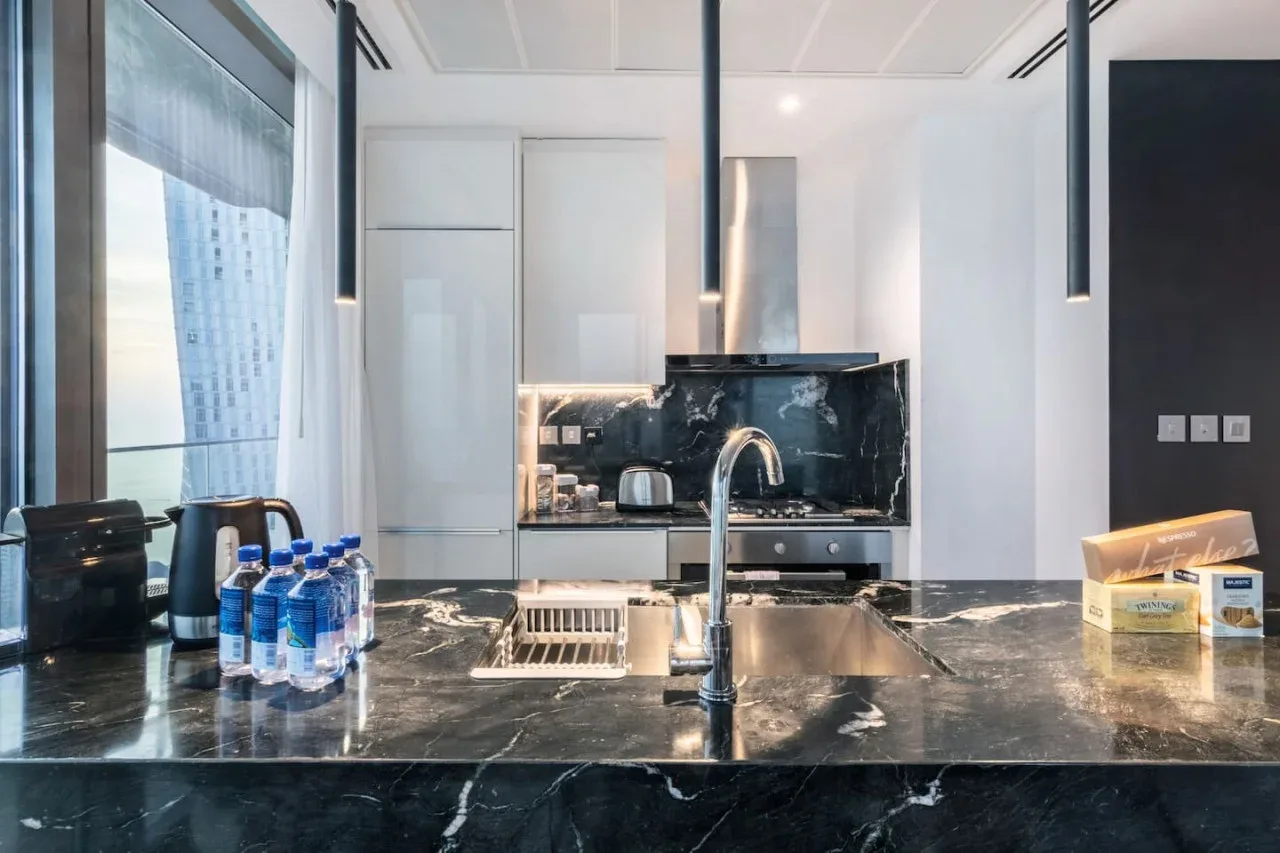 A modern kitchen with a dark stone island and stainless steel appliances.