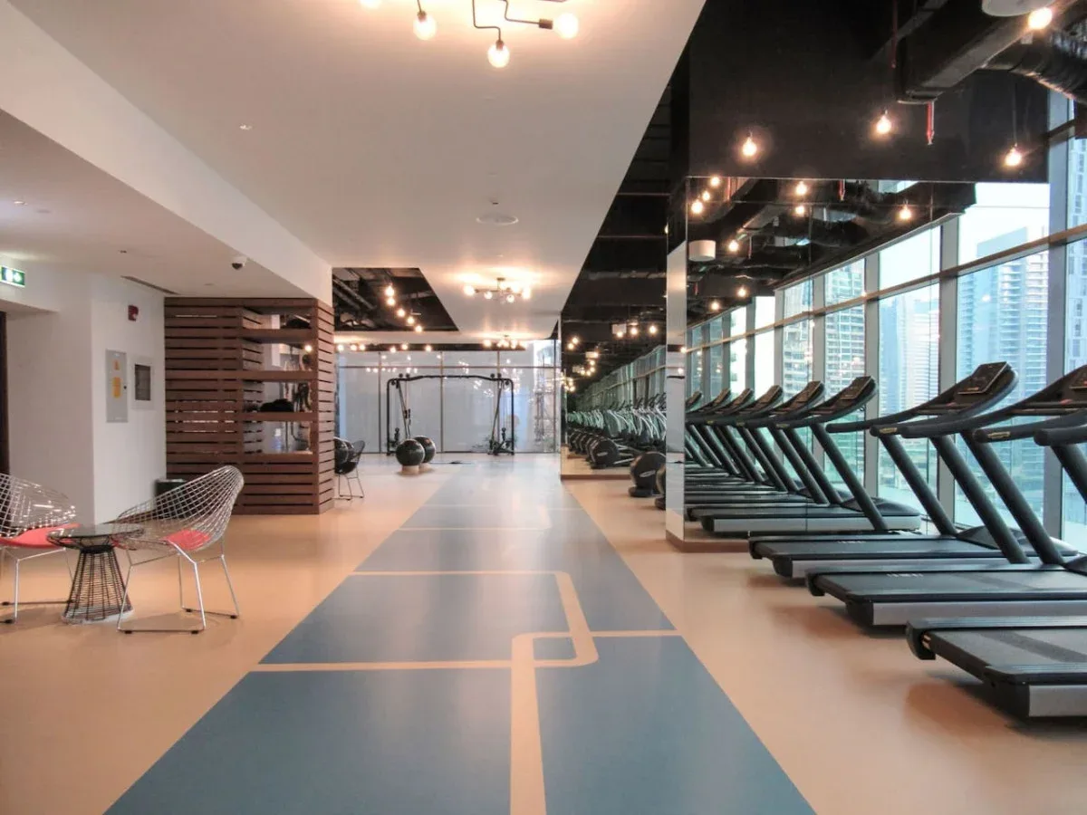 A modern gym with treadmills lined up beside large windows.
