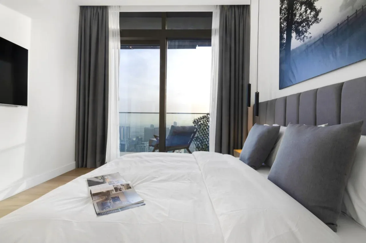 A bedroom with a bed facing glass doors and a balcony.