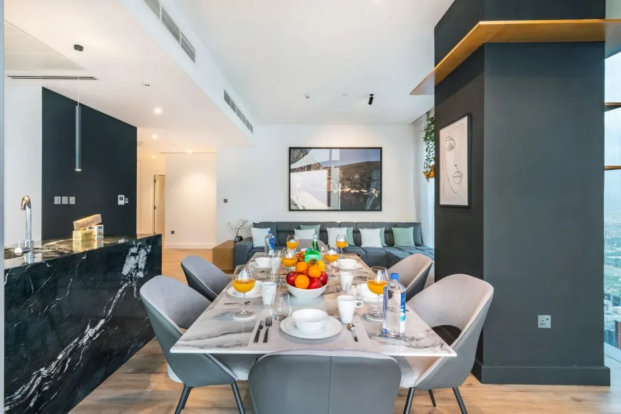 A dining table is set in a bright open-plan living and dining area.