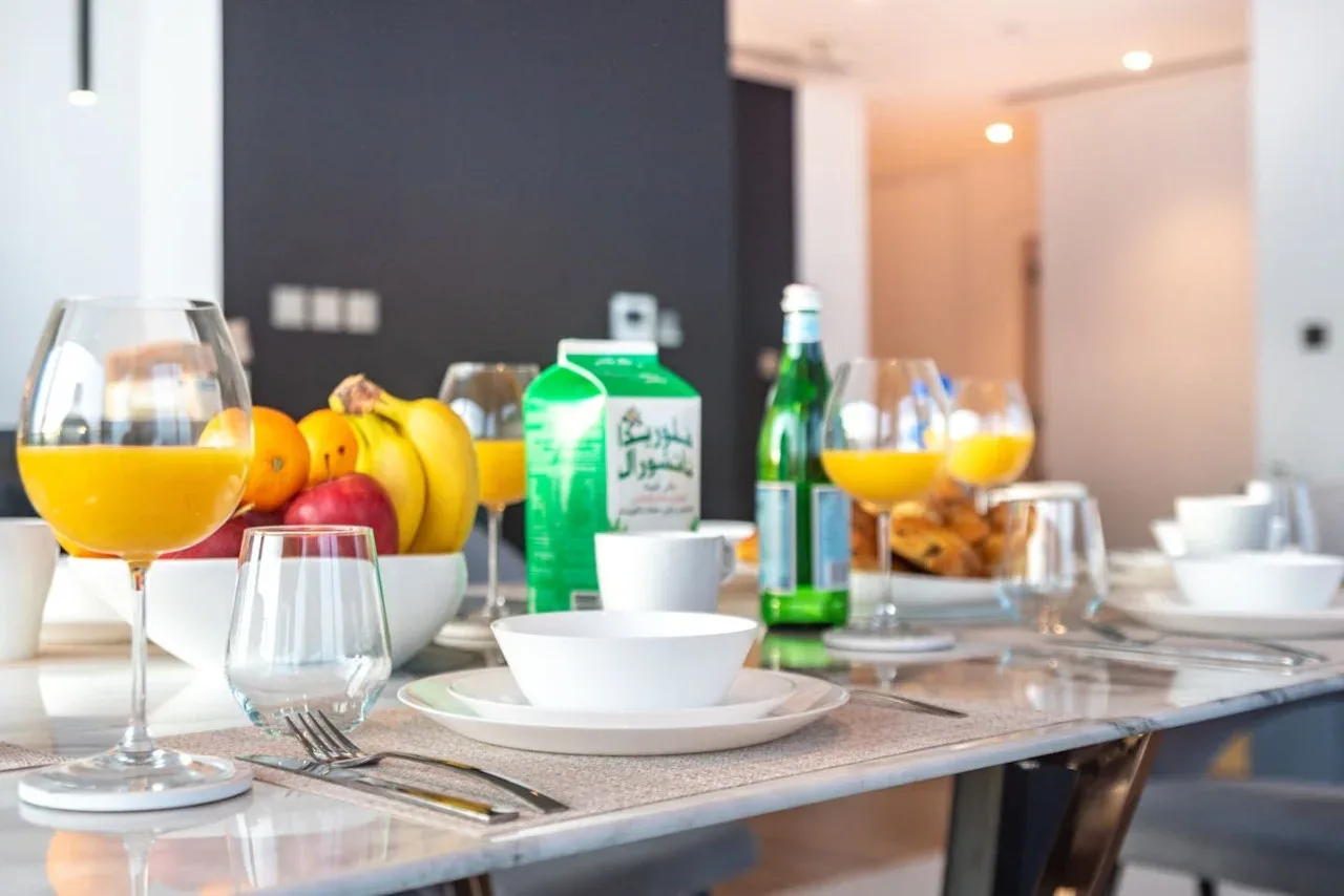 A dining table is set with dishes, fruit, juice, and bottled drinks.