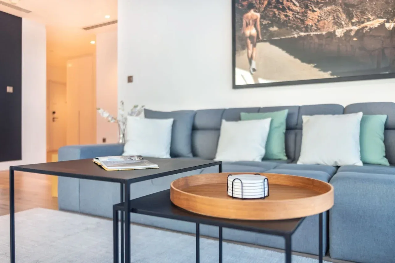 A living room with a blue seating area, coffee tables, and framed wall art.