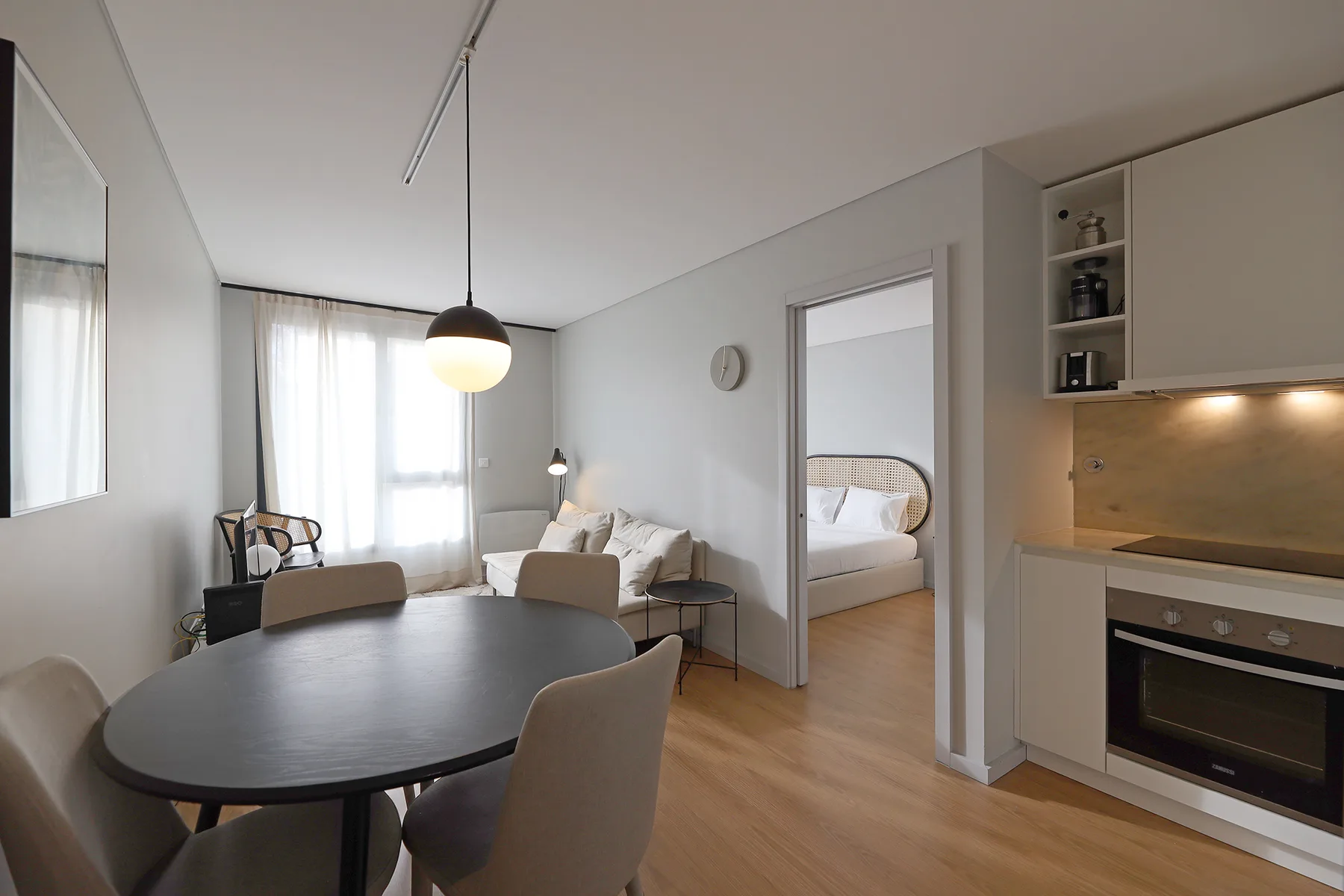 An open-plan living and dining area with a kitchen and bedroom doorway.
