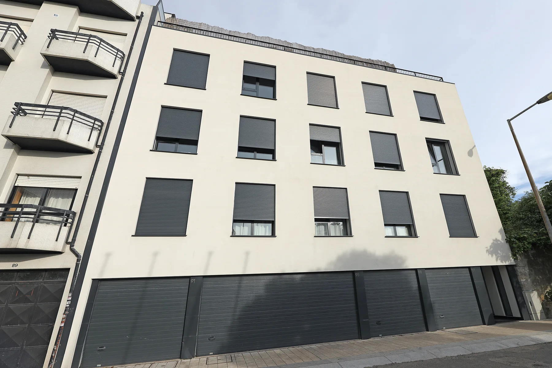 Street view of a modern apartment building with rows of windows.
