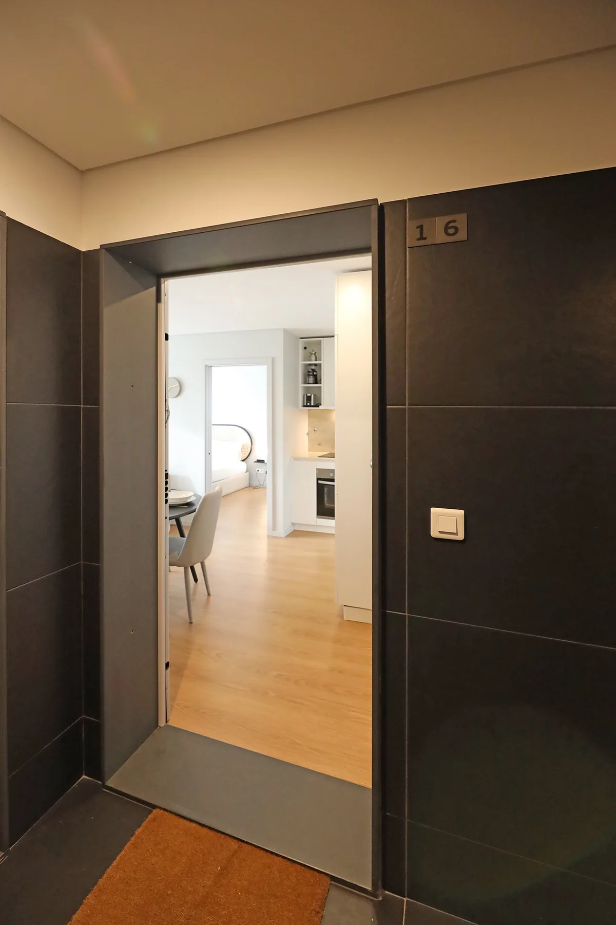 A dark-tiled entryway opens onto a bright room with light wood flooring.