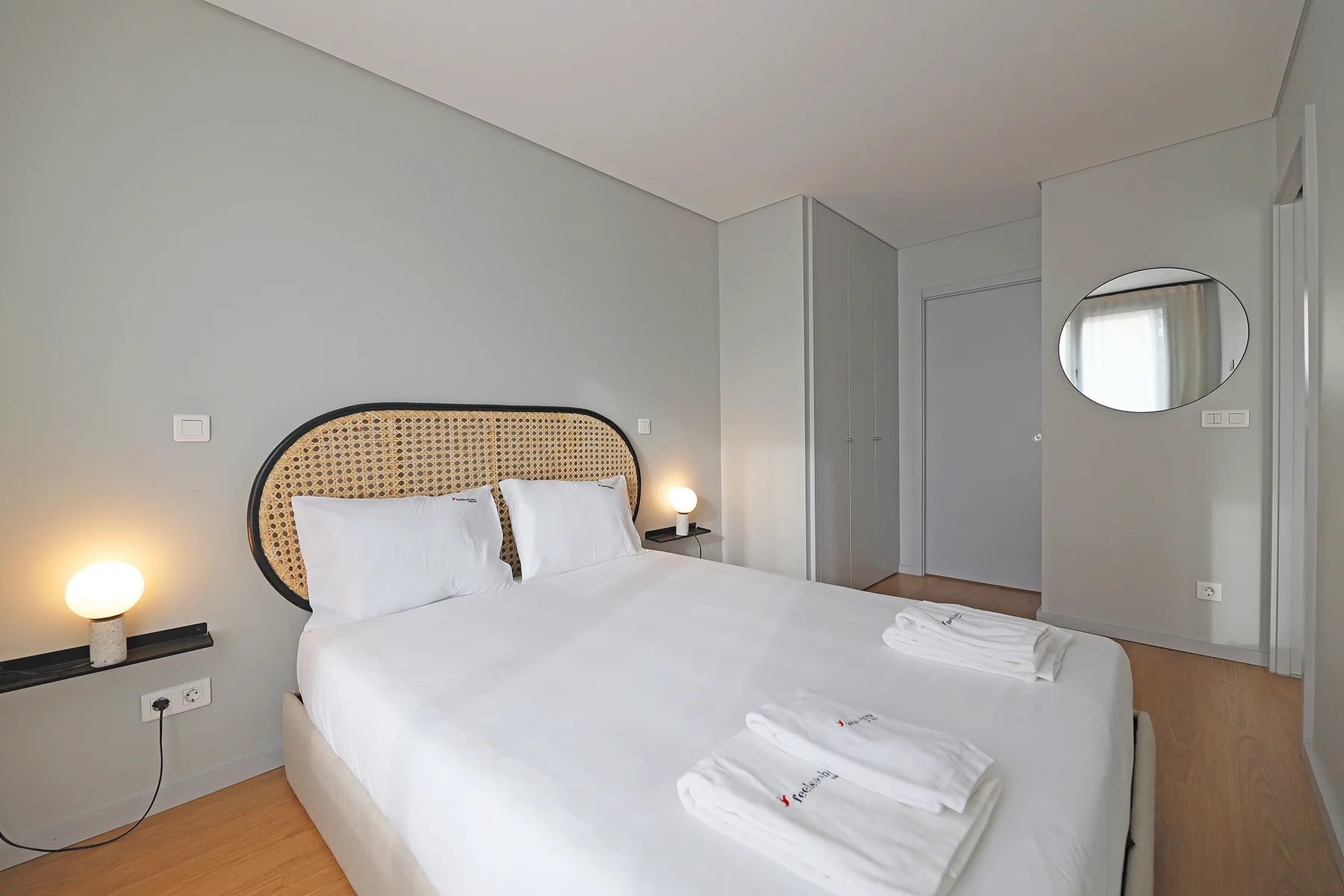 A bedroom with a neatly made bed and folded towels.