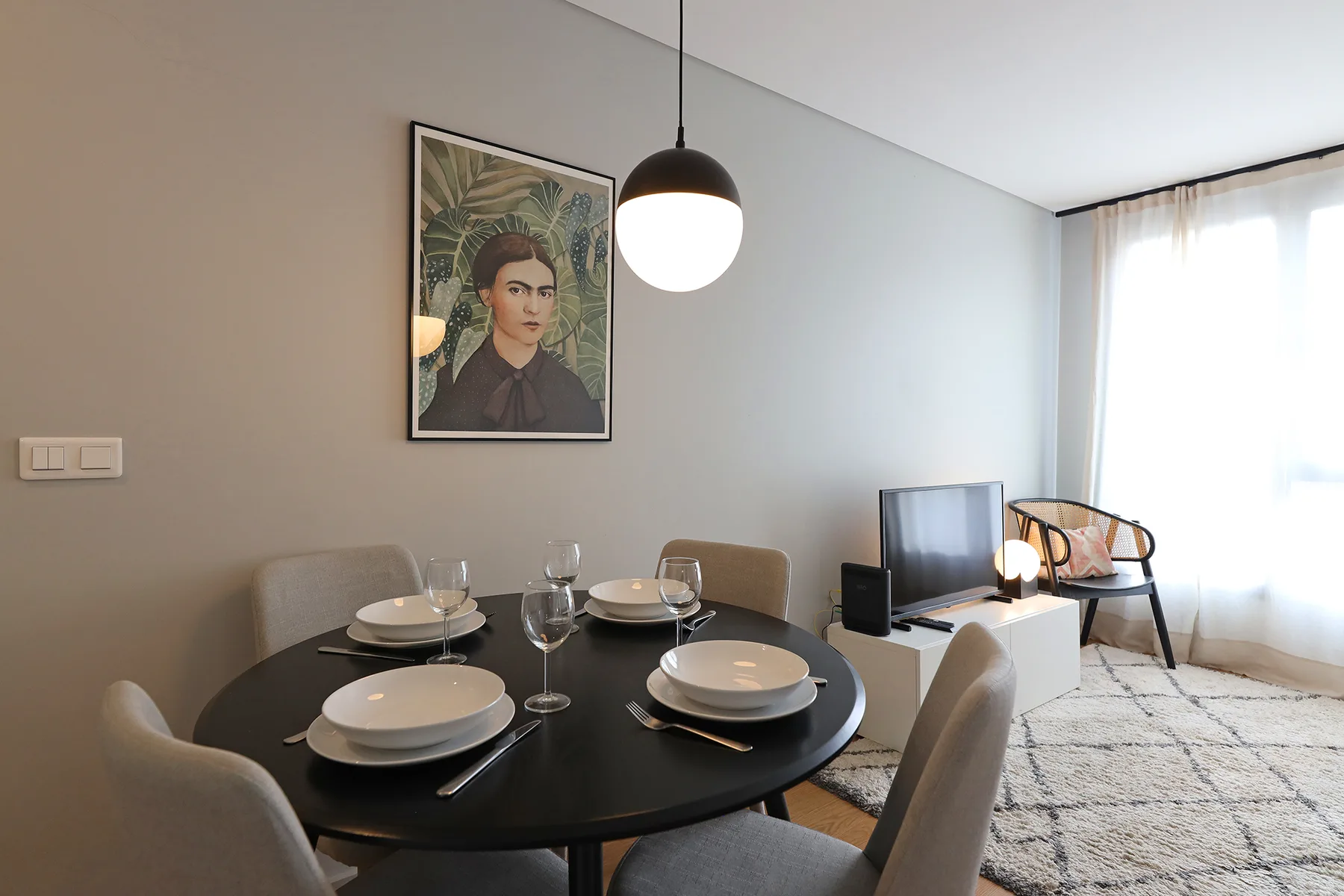 A dining area with a set table beside a bright window.