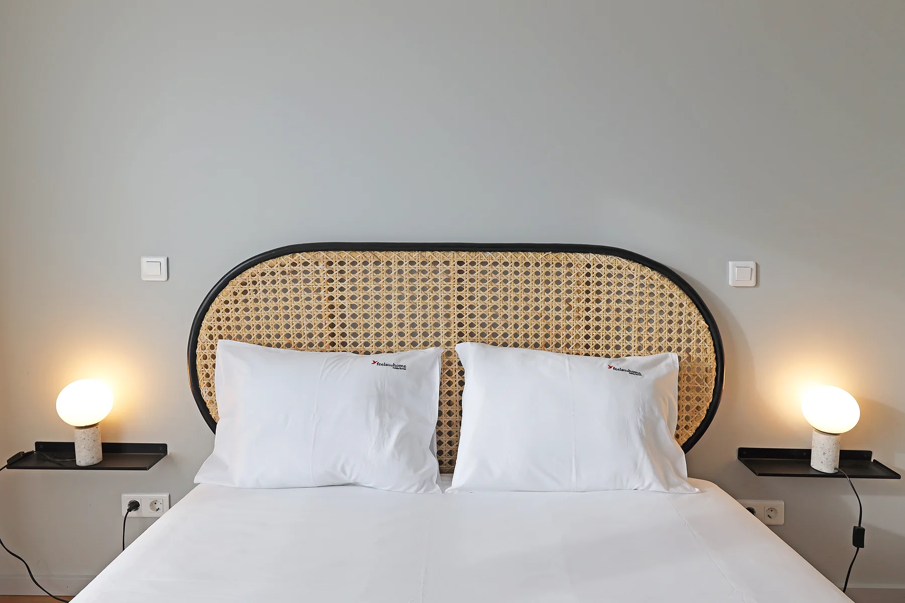 A bedroom with a bed, white bedding, and a woven headboard.