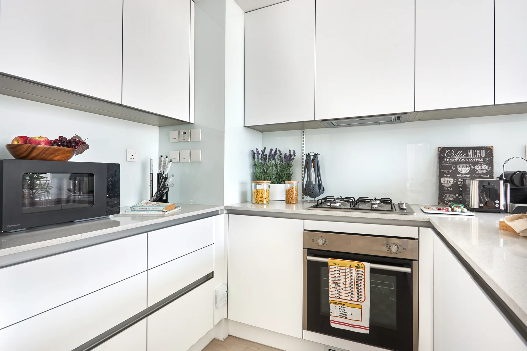 Una cocina moderna con gabinetes blancos, una encimera y electrodomésticos.