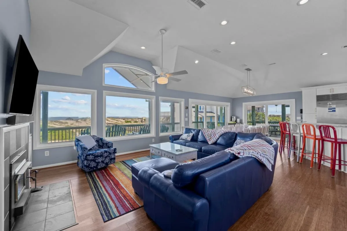 A bright living room with blue seating and large windows overlooking an open landscape.