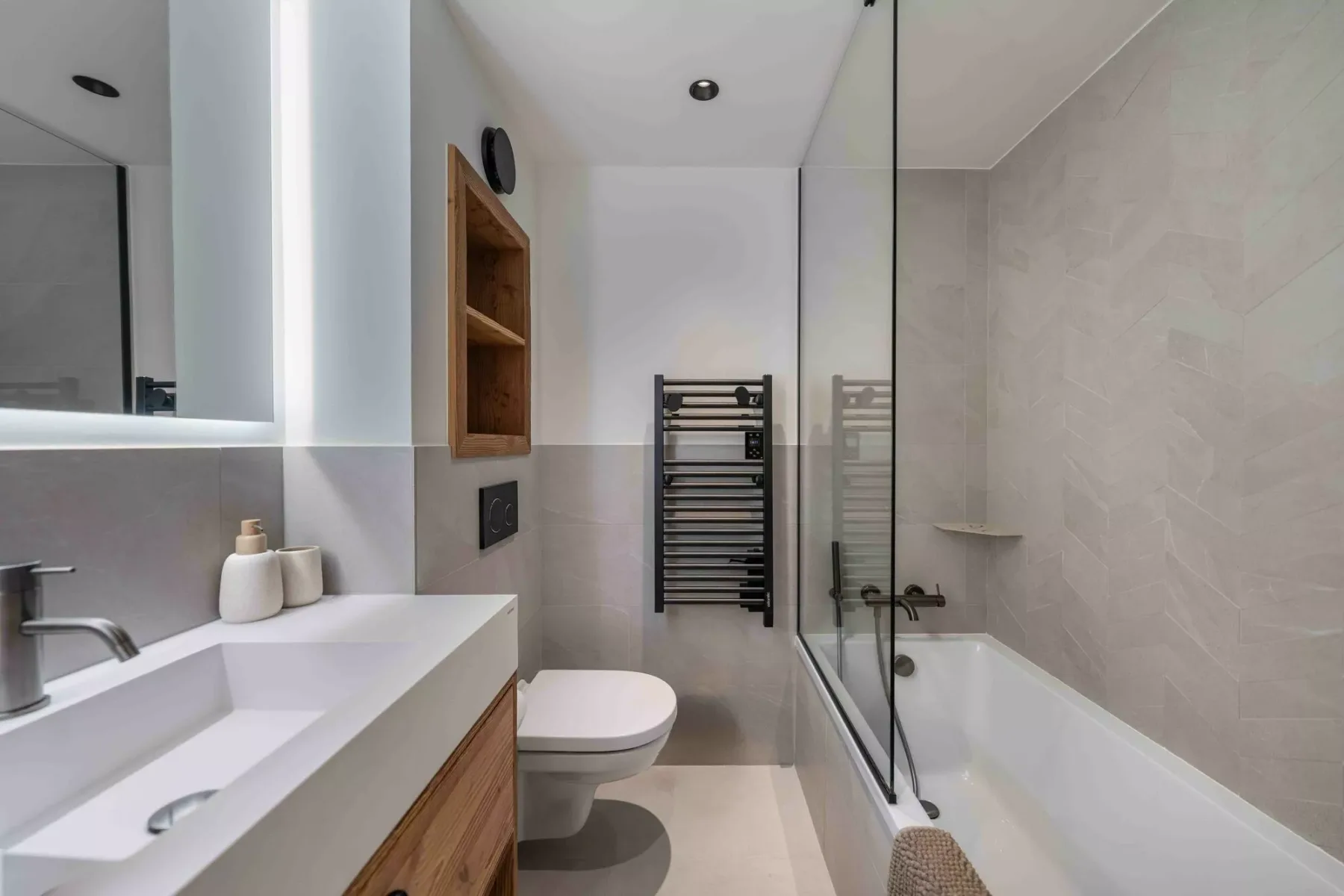 Un baño con bañera, mampara de vidrio y lavabo.