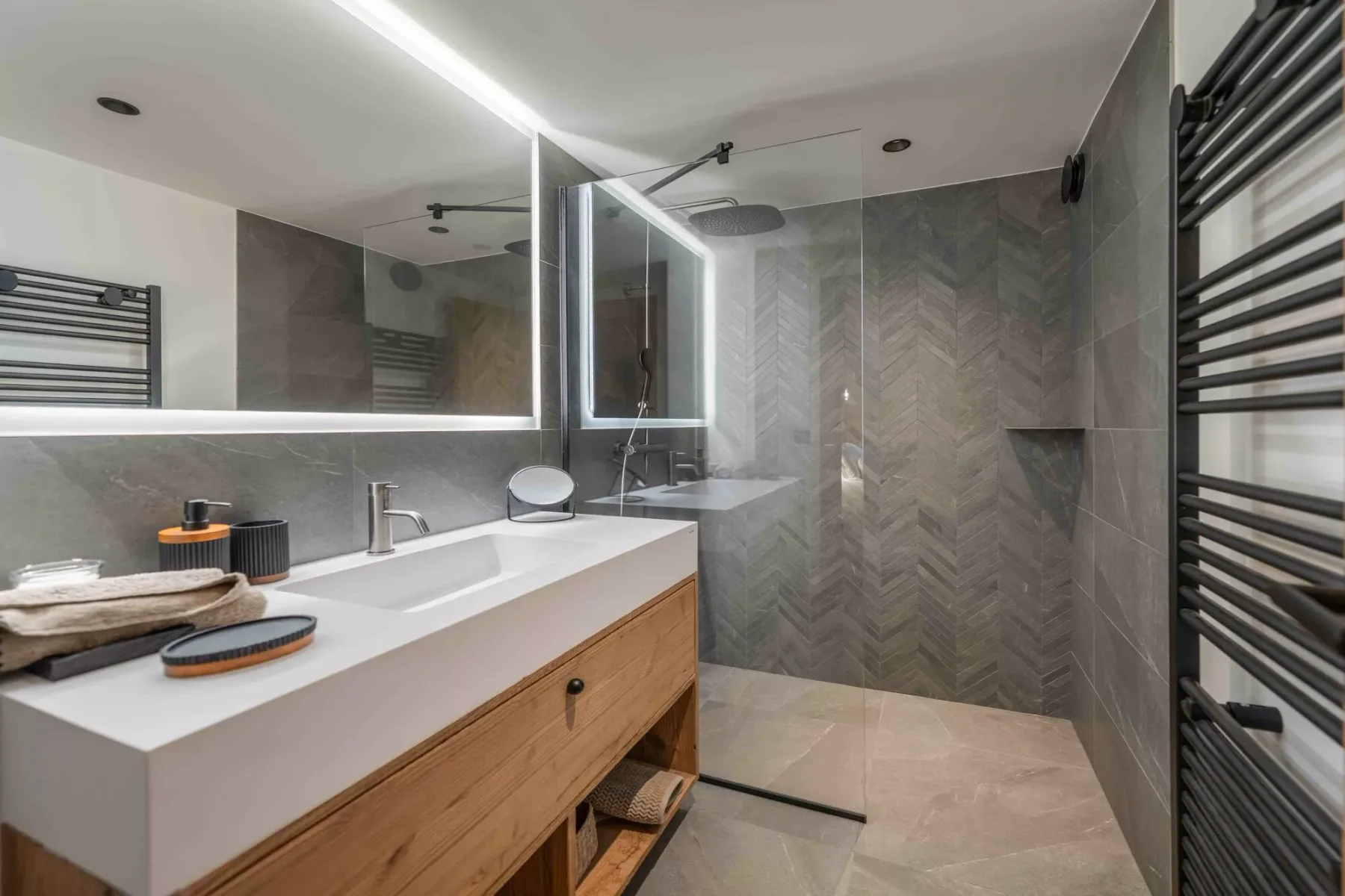 Un baño moderno con un lavabo largo, espejo y ducha de vidrio.