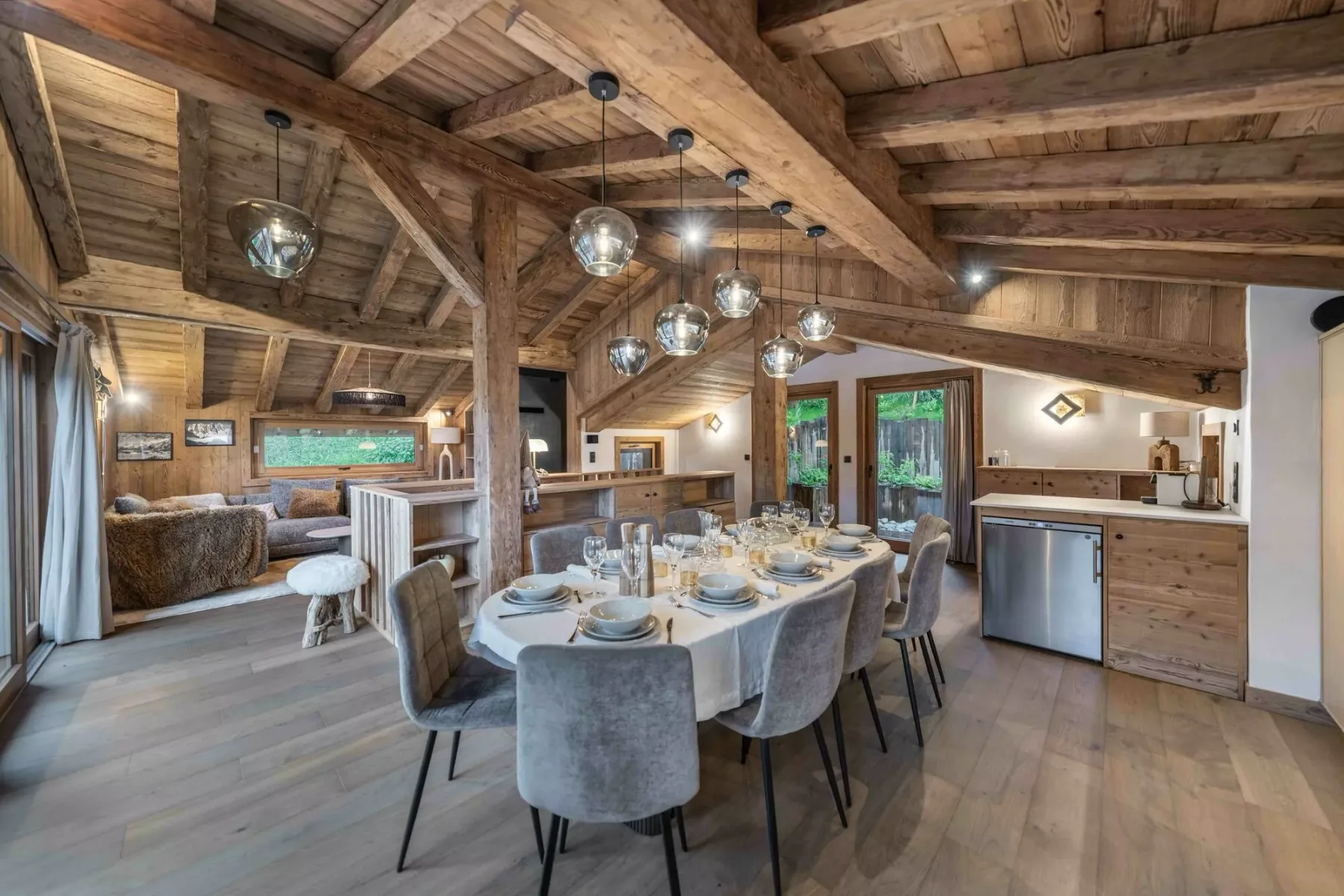 Comedor con una mesa larga y asientos bajo vigas de madera a la vista.