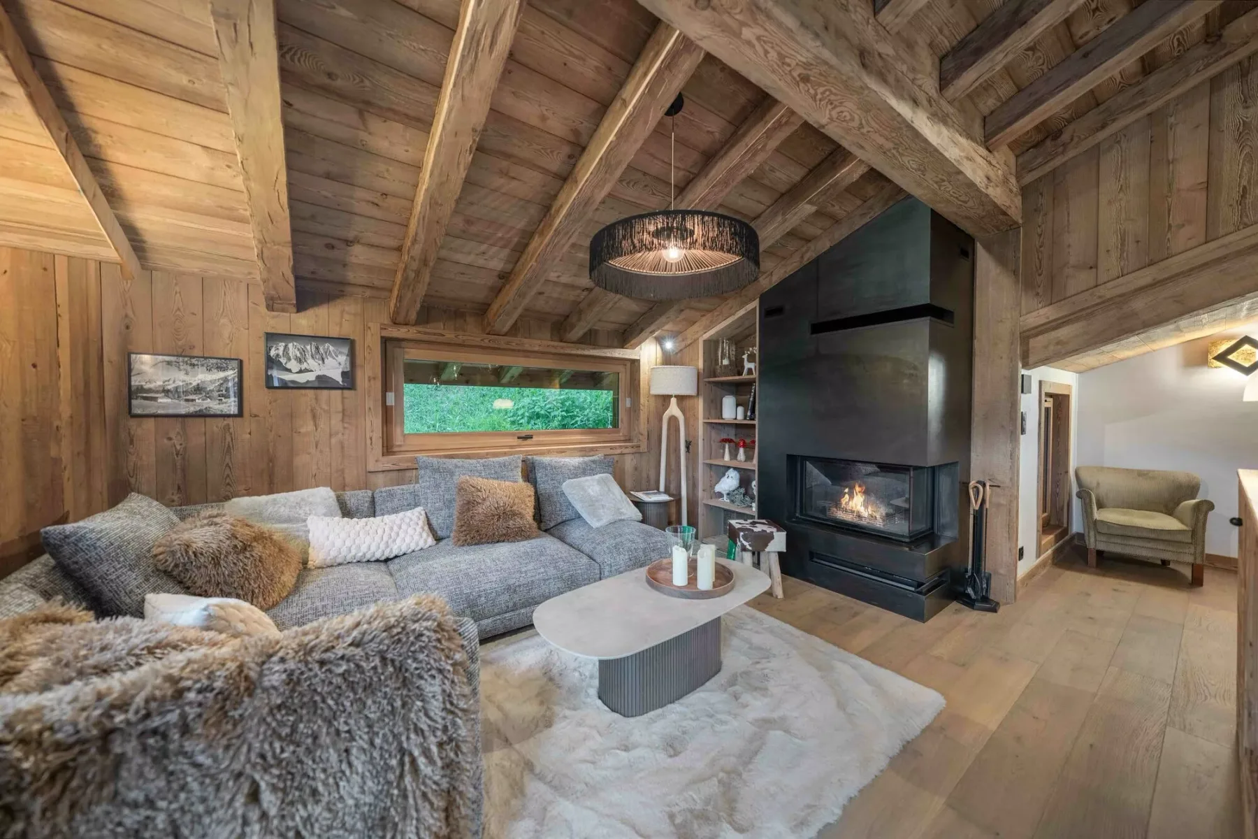 Una sala de estar revestida de madera con asientos seccionales y una chimenea.