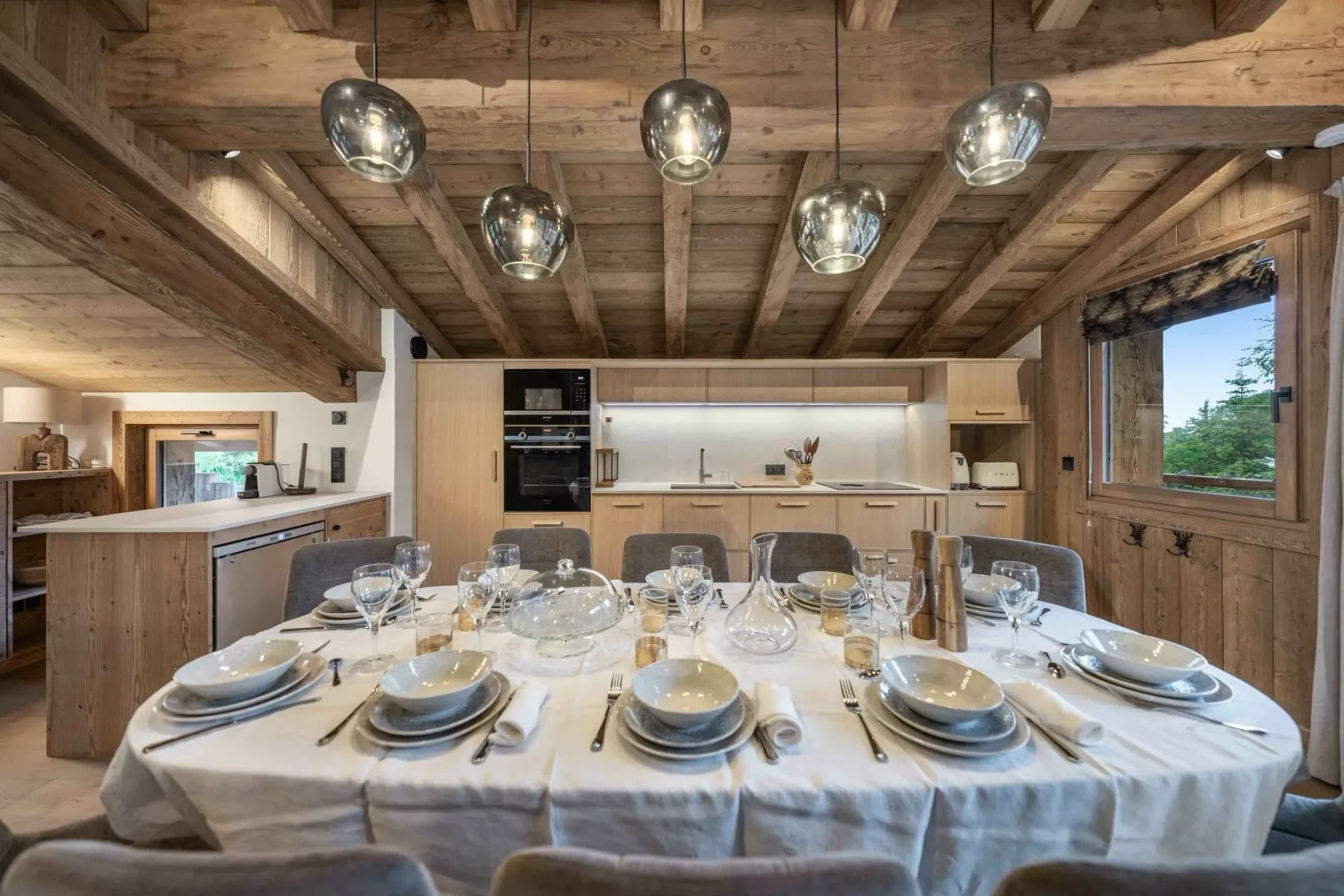 Comedor con una larga mesa puesta bajo vigas de madera expuestas.
