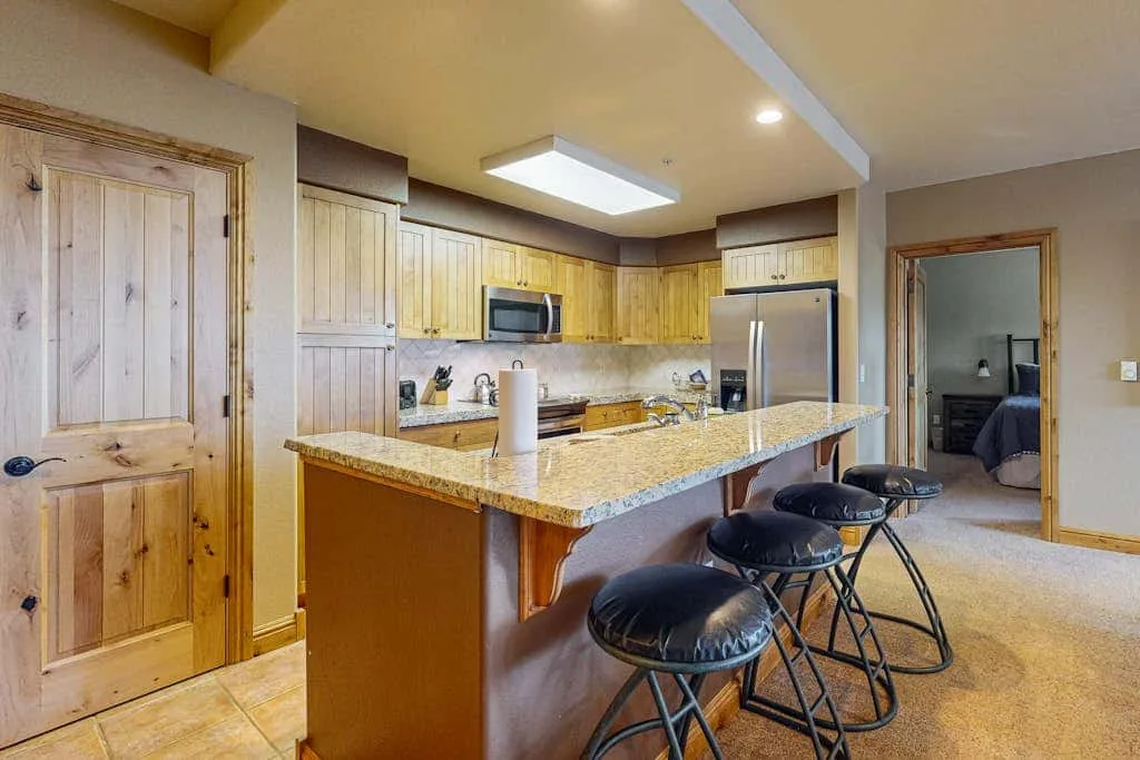 A kitchen with a large island, bar seating, and wooden cabinets.