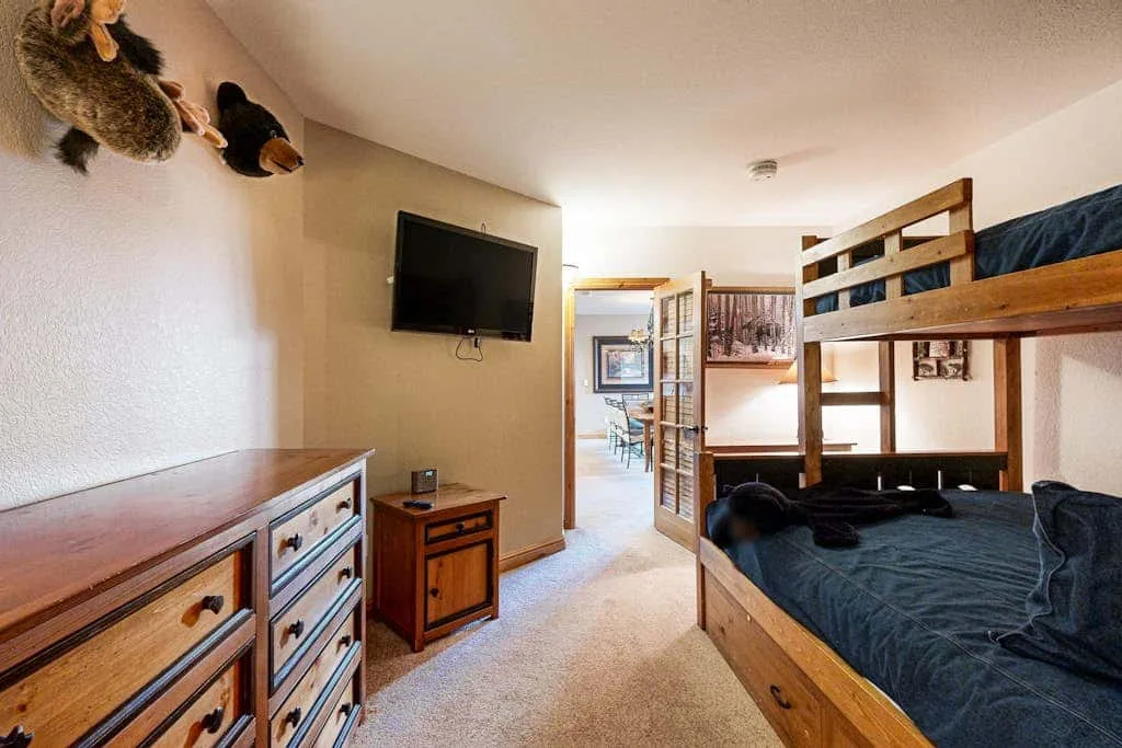 A bedroom with bunk beds, a dresser, and a television.