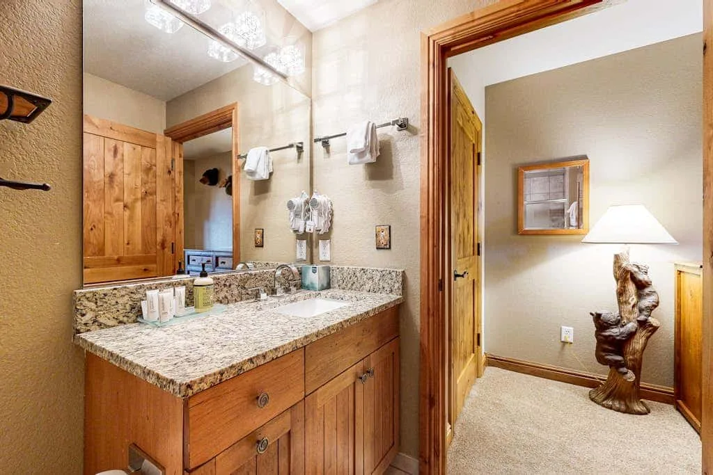 A bathroom vanity with a wide mirror and an open doorway.