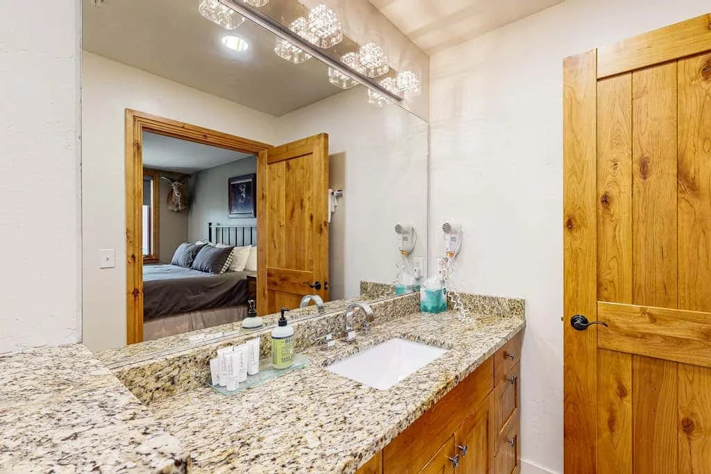 A bathroom vanity with a wide mirror and a granite countertop.