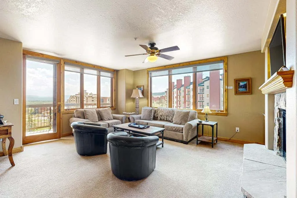 A living room with seating beside large windows overlooking nearby buildings.