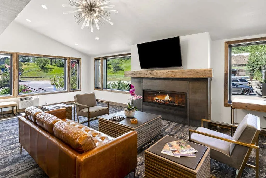 A bright living room with seating arranged around a fireplace and television.