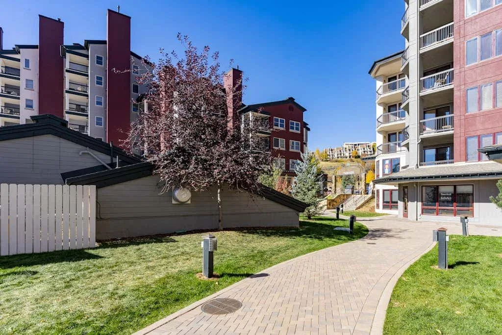 A paved walkway curves through a landscaped courtyard between apartment buildings.