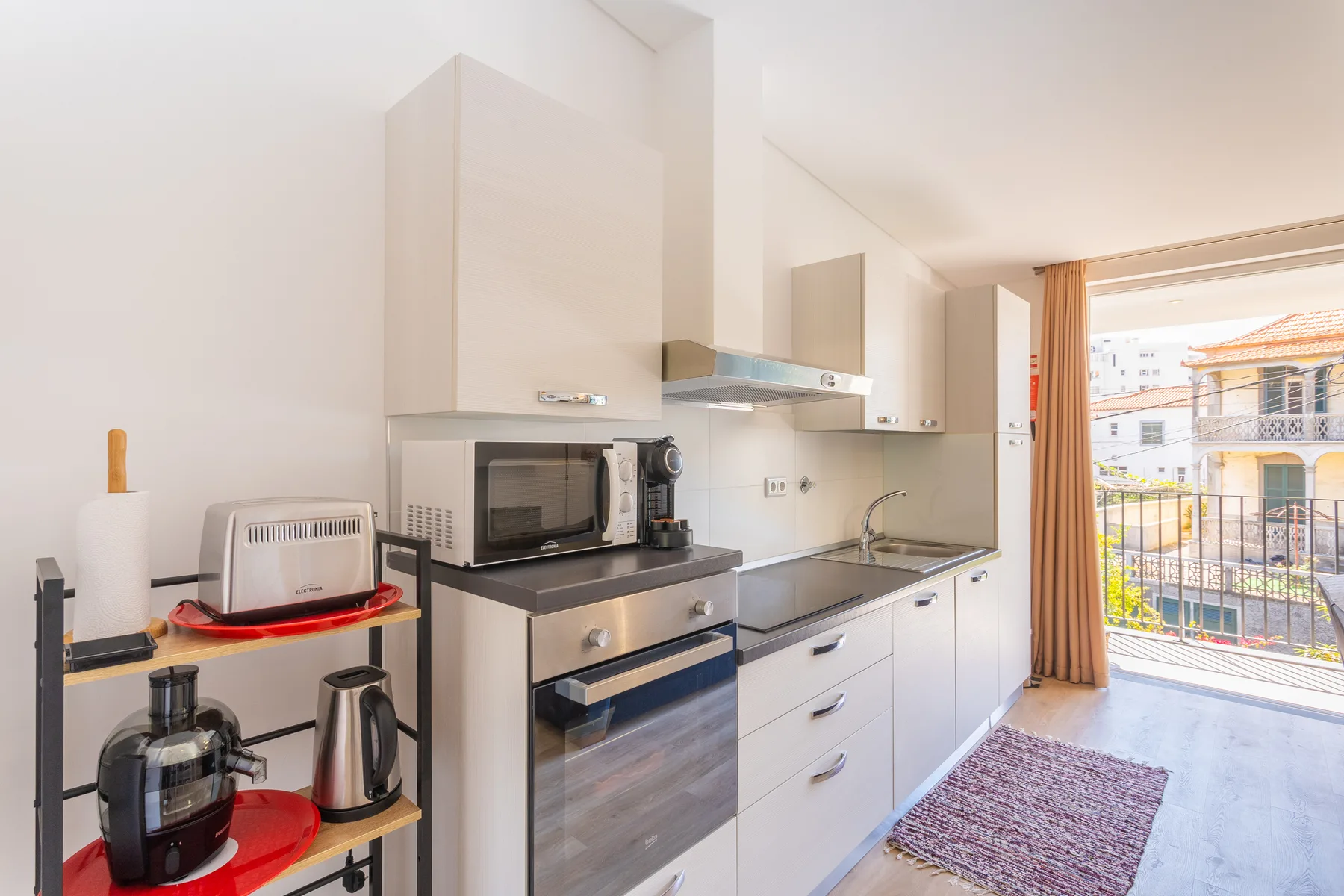 Una cocina compacta con un horno sobre la encimera y vistas al balcón.