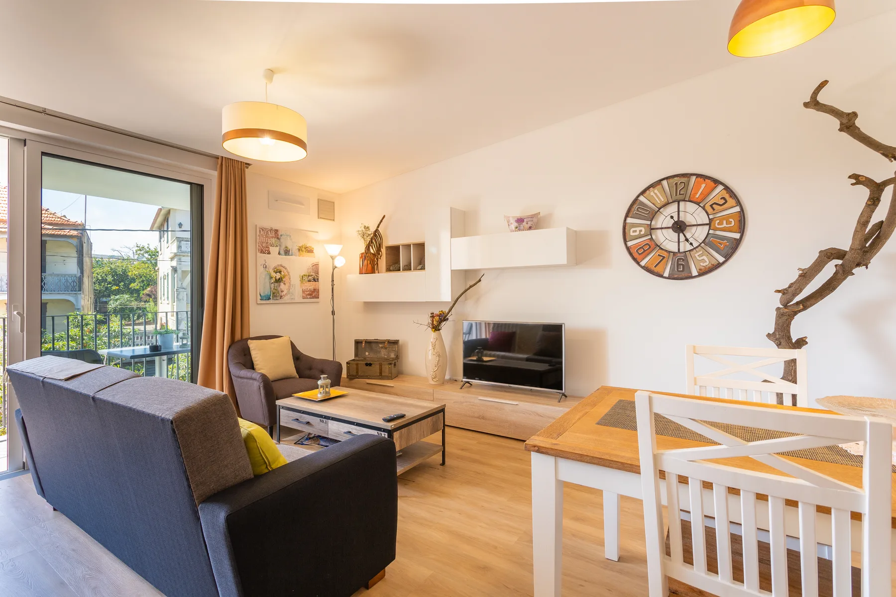 Una sala de estar con asientos, un televisor y una mesa de comedor junto a puertas de cristal.