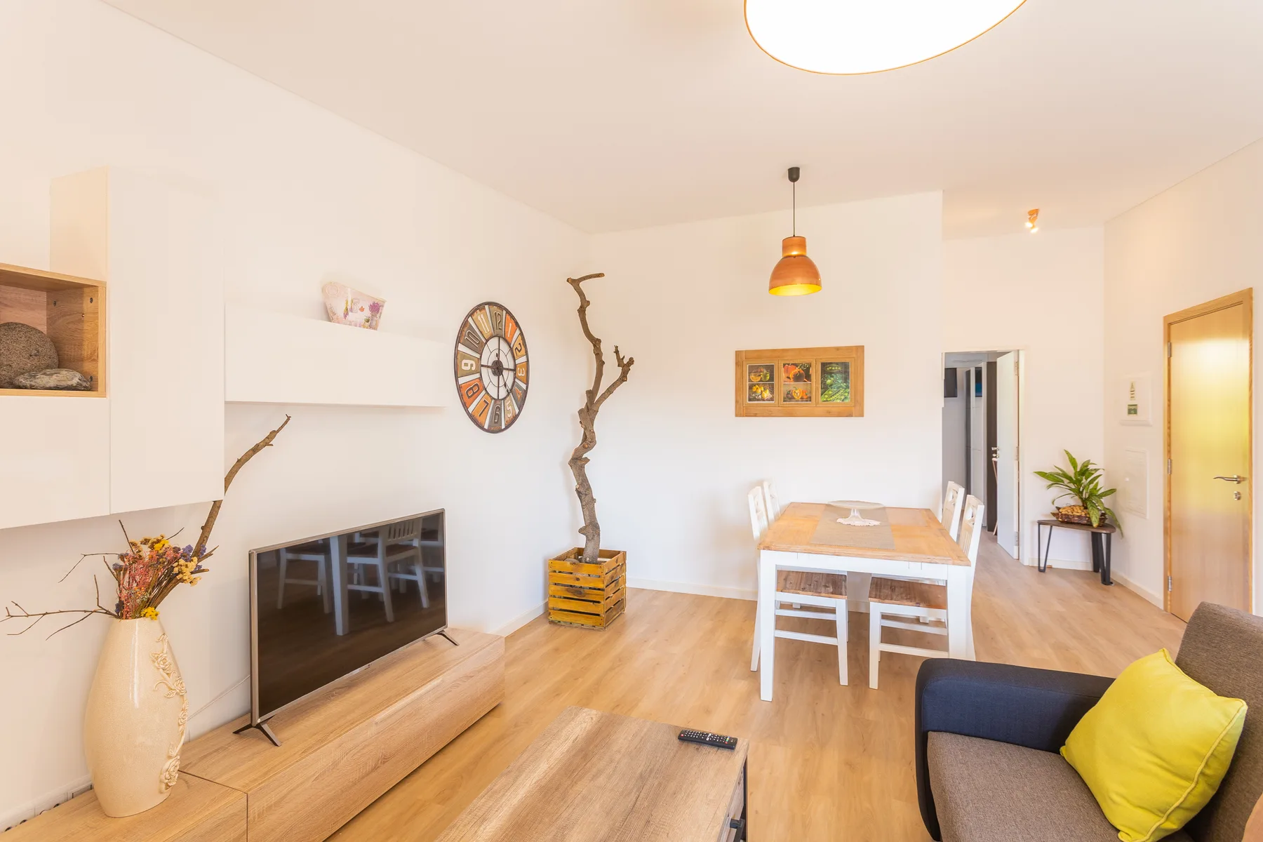 Luminoso espacio de sala y comedor con televisor, mesa de comedor y asientos.