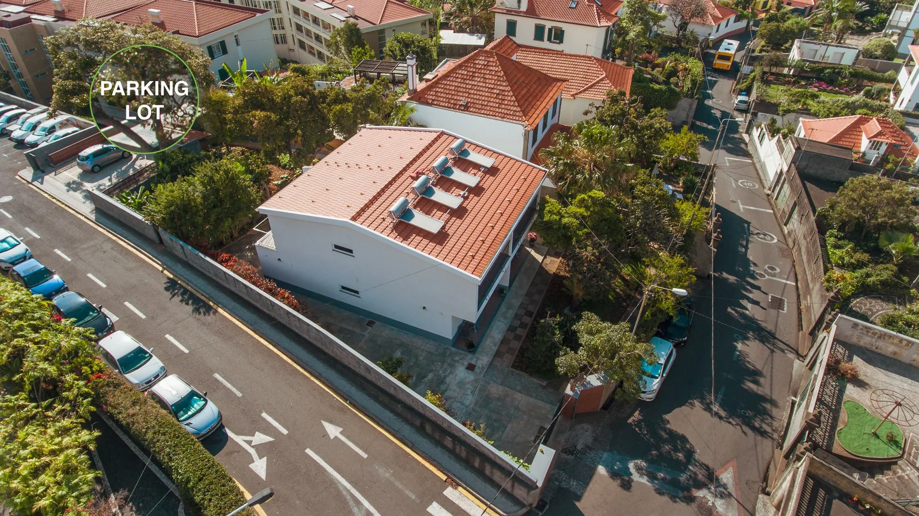 Una vista aérea muestra casas con tejados de tejas rojas junto a una calle y una zona de aparcamiento.