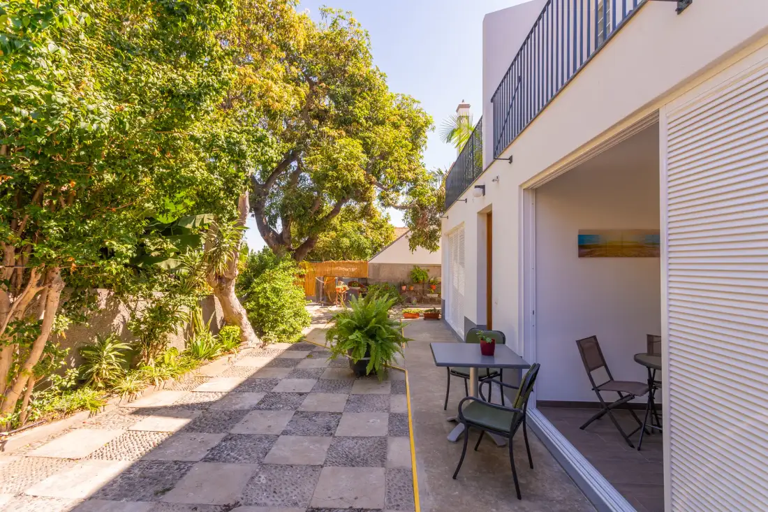 Un patio ajardinado pavimentado con asientos al aire libre junto a un jardín frondoso.