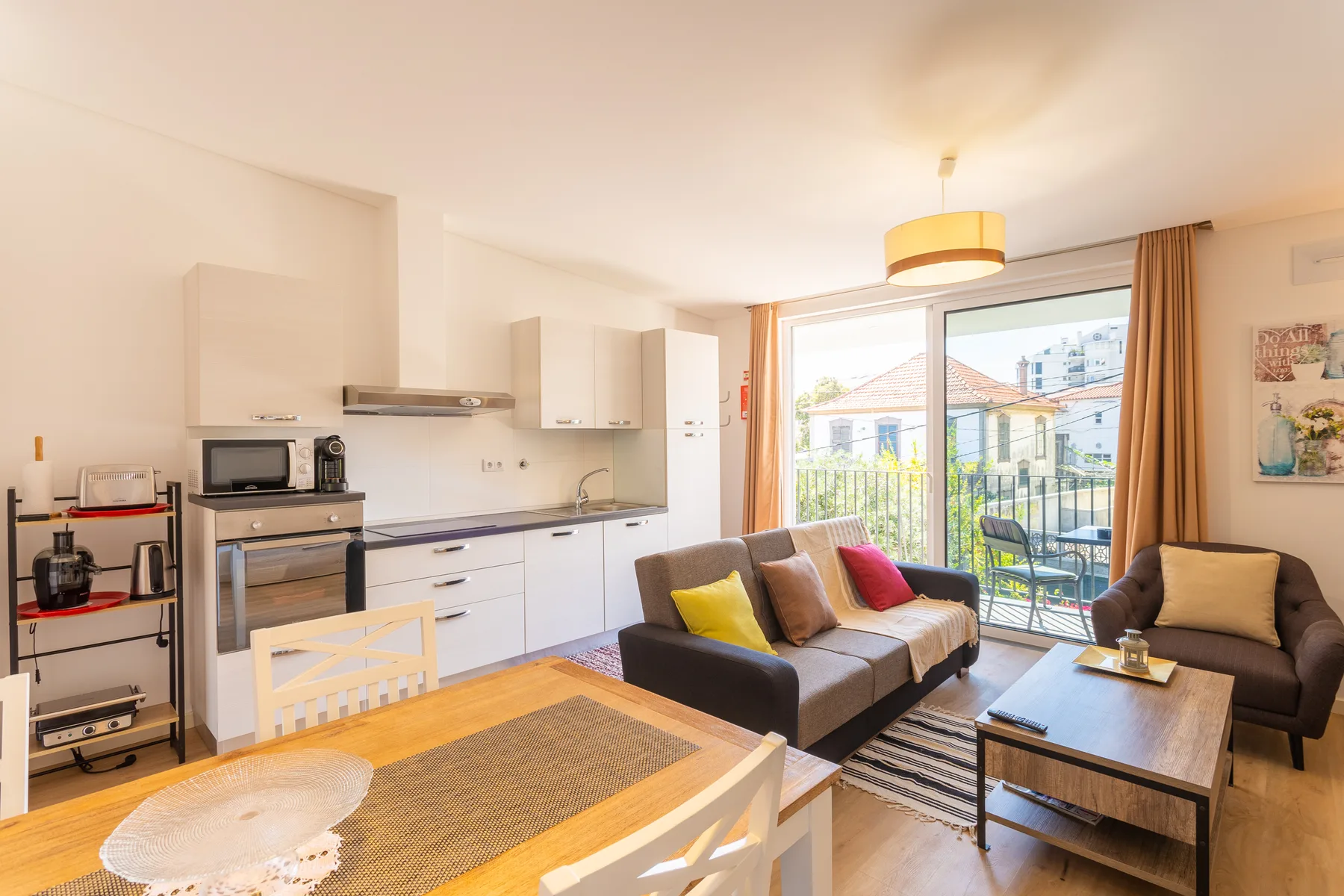 An open-plan living room and kitchen with seating beside large glass doors.