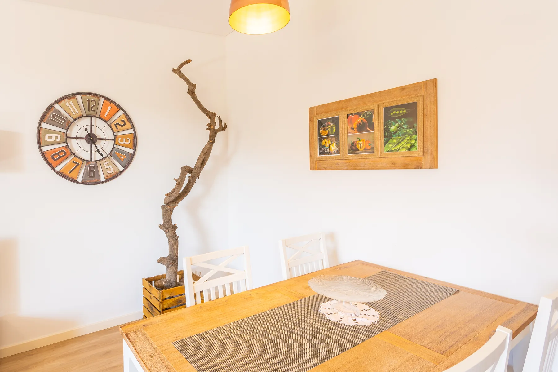 A dining area with a wooden table, woven runner, and wall clock.