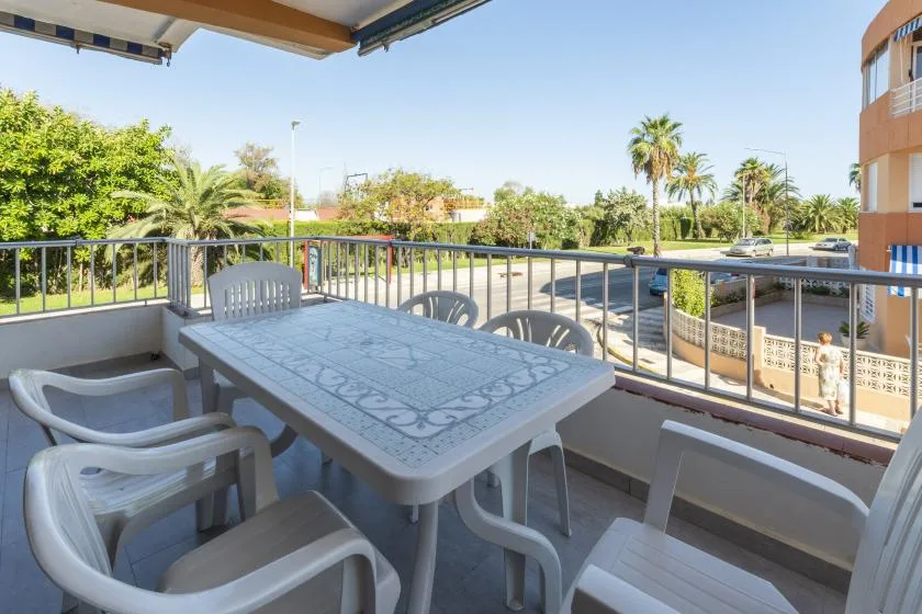 A balcony seating area with a table overlooks a tree-lined street.