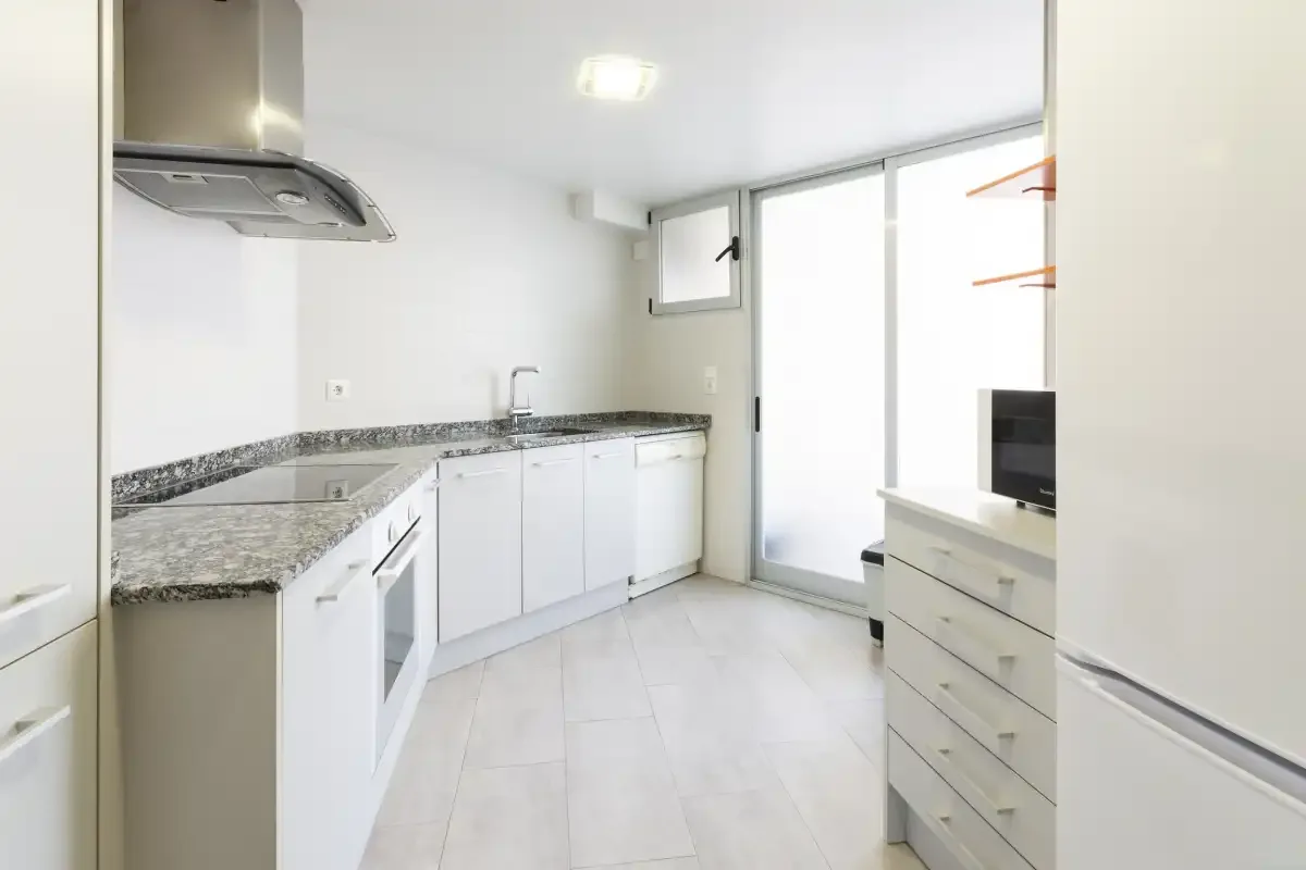 A bright kitchen with white cabinets, a countertop, and a large window.