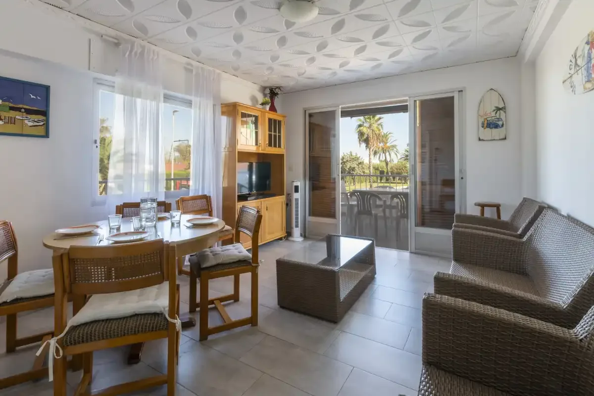 Bright living and dining room with seating and glass doors opening to a balcony.