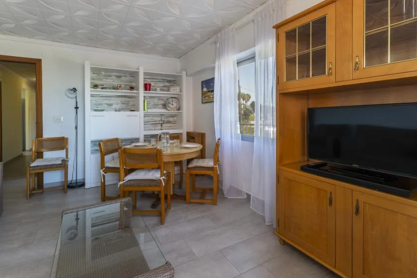 A dining area with a wooden table and chairs beside a television cabinet.