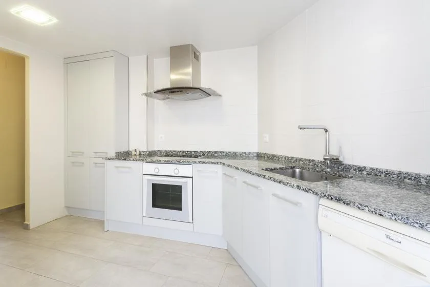 A bright kitchen with white cabinets, a countertop, and a sink.